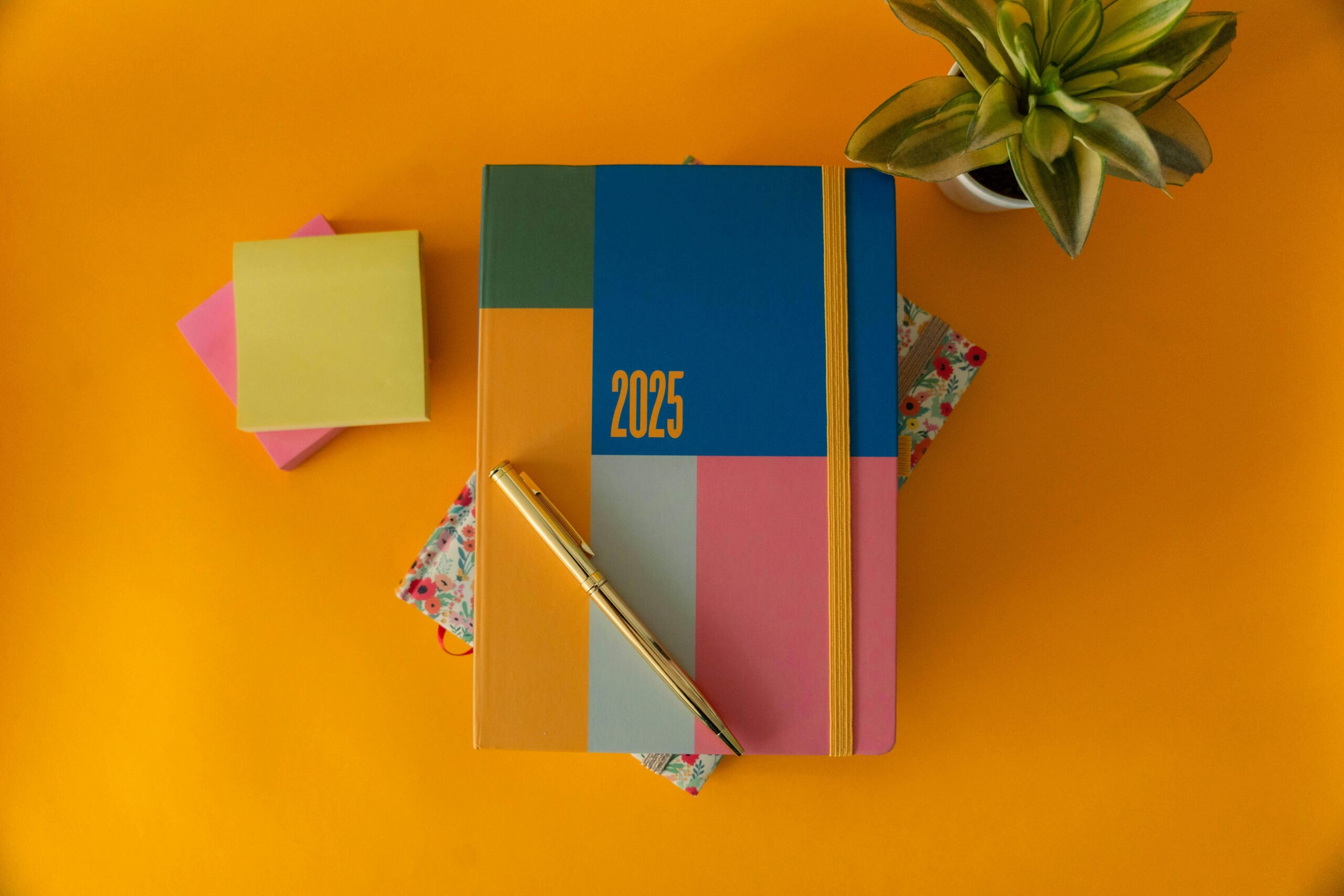 Ein lebendiger Planer für 2025 mit einem Stift auf gelbem Hintergrund, perfekt für die Organisation des Jahres.